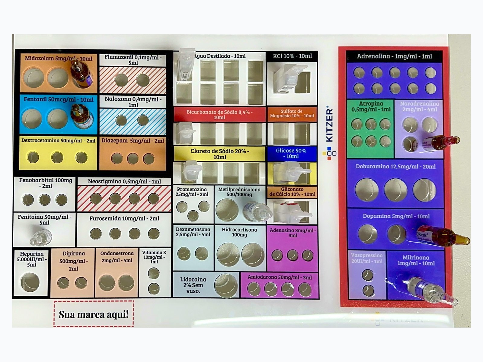 MOGE impresso visto de cima, com nichos coloridos por classe de medicamento e ampolas encaixadas.